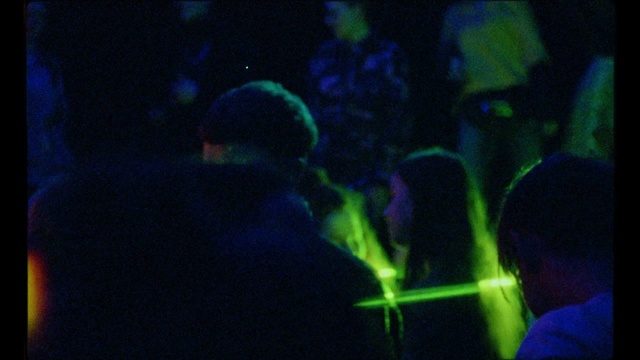 Video Reference: Blue, Green, Light, Organism, Performance, Event, Darkness, Electric blue, Music venue, Nightclub, Person, Indoor, Dark, Screen, Man, Sitting, Front, Looking, Room, Laptop, Monitor, Video, Television, Game, Holding, Lit, Watching, Playing, Computer, Boy, Standing, Using, People, Black, Blurry, Young, Red, Remote, Woman, Living, Wii, Group, White, Aquarium, Reef, Concert