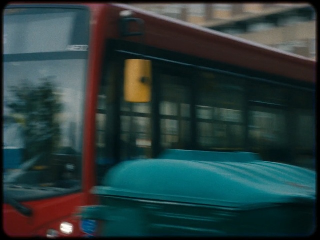 Video Reference: Mode of transport, Transport, Bus, Automotive exterior, Vehicle, Auto part, Tints and shades, Window, Glass, Automotive window part, Person, Outdoor, Building, Street, Car, Blue, Front, Green, City, Red, Sitting, Driving, Double, Woman, Decker, Parked, Stop, Riding, Large, Train, Man, Mirror, White, Standing, Sign, Blurry, Land vehicle, Text