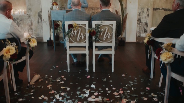 Video Reference: Chair, Floor, Event, Flooring, Room, Furniture, Art, Interior design, Person, Indoor, Table, Living, Sitting, Food, Dining, Small, White, Woman, Holding, Standing, Wooden, Dog, Laying, Man, Plate, People, Kitchen, Painting, Dining table