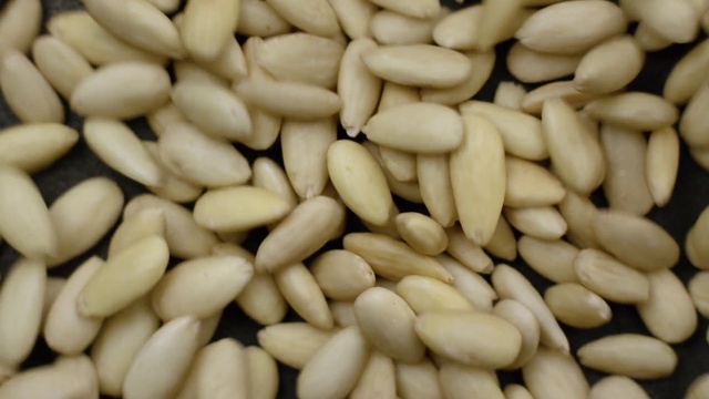 Video Reference: Food, Pine nut, Ingredient, Cuisine, Vegetarian food, Plant, Seed, Produce, Nuts & seeds, Sunflower seed, Nut, Fruit, Pile, Store, Several, Large, Sitting, Topped, Chocolate, Green, Pan, Close, Ready, Counter, Stacked, Covered, Table, Bunch, Plate, Grill, Display, Fries, Many, Oven, Cooking, Group, Sliced, Arranged, Sale