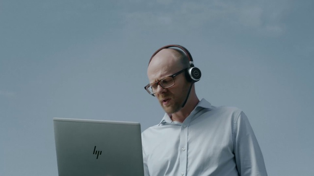 Video Reference: Glasses, Eyewear, Audio equipment, Technology, Electronic device, Gadget, White-collar worker, Person, Man, Holding, Standing, Looking, Laptop, Front, Wearing, Suit, Shirt, Computer, Hand, Giving, Kite, Large, Screen, Table, Woman, Board, White, Flying, Human face