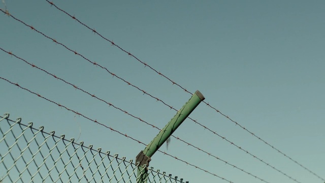 Video Reference: wire fencing, sky, barbed wire, fence, wire, overhead power line, line, outdoor structure, electrical supply, public utility