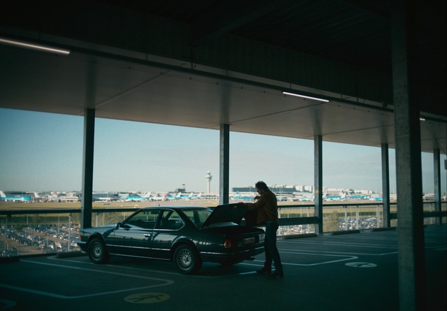 Video Reference: Vehicle, Vehicle door, Car, Luxury vehicle, Snapshot, Sky, Architecture, Building, Executive car, Shade, Road, Man, Board, Green, Luggage, Bridge, Standing, Parked, Table, Airplane, Air, Large, Water, Plane, Riding, Room, City, Doing, Tarmac, Bus, Land vehicle, Wheel, Street, Tire