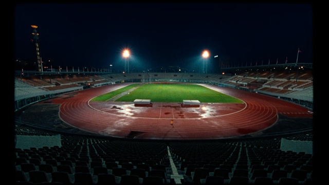 Video Reference: Sport venue, Stadium, Arena, Night, Atmosphere, Sky, Race track, Soccer-specific stadium, Track and field athletics, Sports, Outdoor, Sitting, Table, Light, Large, Red, Plane, Lit, Runway, Green, Track, White, Water, Airplane, Street, Blue, Ocean