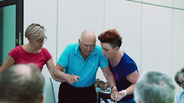 Video Reference: Community, Event, Leisure, Physical fitness, Competition event, Service, Team, Training, Person, Indoor, Man, Standing, Woman, Holding, People, Court, Preparing, Young, Racket, Kitchen, Playing, Luggage, Group, Older, Boy, Game, Table, Suitcase, Room, Cake, Cutting, Video, Computer, Clothing