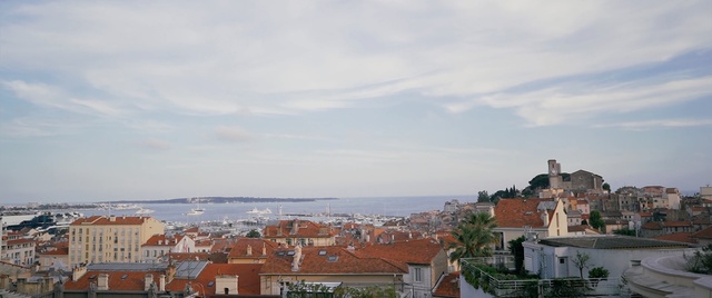 Video Reference: Sky, Town, Roof, Urban area, City, Horizon, Human settlement, Cloud, Neighbourhood, Sea, Outdoor, Building, House, Water, Train, Track, Large, Small, Boat, Street, Sitting, View, Harbor, Body, Orange, White, Old, Traveling, Parked, Field, Yellow, River, Road, Traffic, Red, Docked, Ocean, Group, Clock, Riding, Landscape