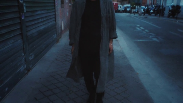 Video Reference: Black, Standing, Light, Snapshot, Shadow, Darkness, Fashion, Atmosphere, Street, Photography, Outdoor, Person, Sidewalk, Building, Holding, Man, Walking, Woman, Wearing, Umbrella, Red, Rain, City, Coat, Clothing, Suit, Jacket, Trousers, Dress, Footwear, Street fashion