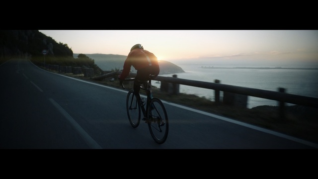 Video Reference: Bicycle, Cycling, Cycle sport, Road cycling, Road bicycle, Vehicle, Mode of transport, Recreation, Outdoor recreation, Racing bicycle, Outdoor, Man, Sunset, Water, Riding, Surfing, Street, Board, Beach, Orange, Sun, Road, Yellow, Standing, Ocean, Traffic, Parked, Bike, Bicycle wheel, Sports equipment, Land vehicle, Wheel