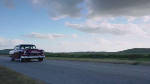 Video Reference: Land vehicle, Vehicle, Car, Classic car, Full-size car, Sedan, Classic, Antique car, Vintage car, Coupé, Outdoor, Road, Grass, Cloudy, Clouds, Truck, Driving, Sitting, Parked, Red, Large, View, White, Plane, Green, Man, Street, Riding, Runway, Airplane, Traffic, Water, Highway, Field, Sign, Board, Blue, Tarmac, Sky, Wheel, Auto part, Way, Day