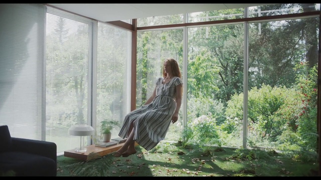 Video Reference: Nature, Tree, Sitting, Sunlight, Window, Adaptation, Organism, Long hair, Interior design, House, Indoor, Building, Looking, Table, Living, Room, Front, Open, Large, Glass, Standing, Water, White, Girl, Fashion, Clothing, Person, Plant, Woman, Furniture, Dress