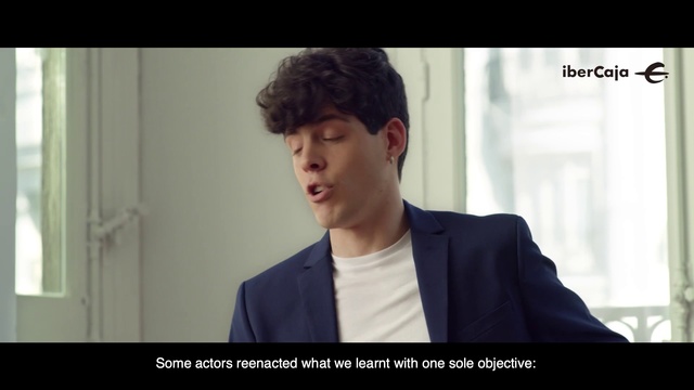 Video Reference: Facial expression, Forehead, Gentleman, Snapshot, Chin, White-collar worker, Human, Cool, Photo caption, Jaw, Person, Indoor, Window, Man, Clothing, Front, Looking, Black, Suit, Shirt, Young, Standing, Sitting, Laptop, Wearing, Screen, Computer, Table, Holding, Woman, Boy, White, Room, Screenshot, Human face, Text, Portrait