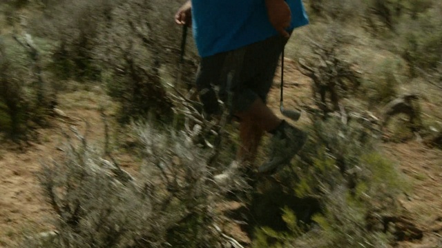 Video Reference: Tree, Adventure, Organism, Grass, Recreation, Soil, Geological phenomenon, Trail, Forest, Landscape, Outdoor, Person, Man, Riding, Young, Hill, Shirt, Mountain, Board, Jumping, Walking, Air, Doing, Standing, Holding, Blue, Flying, Dirt, Ramp, Cat, Trick, Hiking, Clothing, Footwear, Wooded