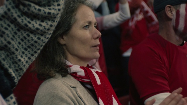 Video Reference: Red, Fun, Event, Performance, Crowd, Person, Indoor, Woman, Wearing, Holding, Man, Looking, Young, Standing, Glasses, People, Sitting, Shirt, Girl, Dressed, Room, Playing, Suit, Game, Video, White, Hat, Phone, Human face, Clothing, Smile