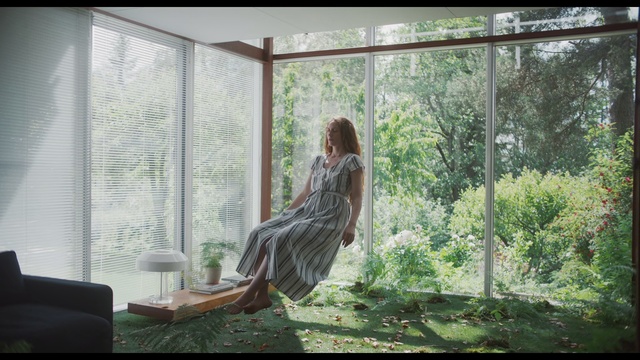 Video Reference: Nature, Tree, Adaptation, Sunlight, Sitting, Window, Organism, Plant, Long hair, Interior design, Indoor, Building, Looking, Living, Table, Room, Front, Open, Large, Glass, Standing, Sun, White, Curtain, Girl, Fashion, Clothing, Person, Woman, Furniture