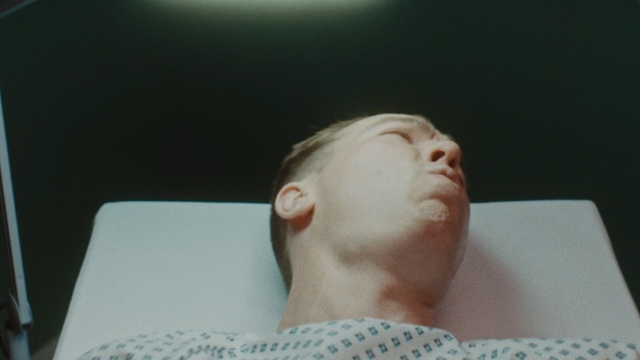 Video Reference: Face, Hair, Neck, Skin, Cheek, Head, Nose, Forehead, Chin, Ear, Person, Indoor, Man, Sitting, Eating, Looking, Table, Holding, Food, Front, Young, Piece, Laptop, Shirt, Computer, Glasses, Mouth, Woman, Teeth, Wearing, Donut, Cake, White, Pizza, Brushing, Plate, Human face