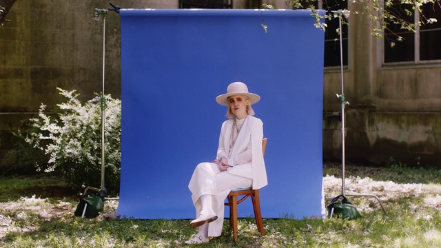 Video Reference: Blue, Sitting, Painting, Grass, Photography, Furniture, Art, Leisure, Artist, Illustration, Outdoor, Building, Man, Front, Woman, Hat, Old, Standing, White, Wearing, Bench, Young, Holding, Table, Field, Snow, Fashion accessory, Sun hat, Fedora, Cowboy hat, Clothing, Person, Smile, Human face, Sombrero