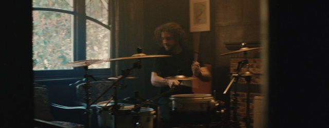 Video Reference: Musician, Drums, Music, Percussionist, Percussion, Drum, Musical instrument, Performance, Drummer, Timbales, Indoor, Person, Man, Window, Food, Preparing, Table, Kitchen, Woman, Front, Shirt, Holding, Standing, Cooking, Large, Room, Pan, Stove, Blue, Plate, Concert, Band, Live music, Gig, Cymbal, Drumhead, Tom-tom drum, Membranophone, Idiophone, Snare drum, Bass drum, Microphone, Hi-hat, Guitar, Drum stick, Percussion mallet