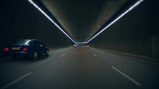 Video Reference: Road, Mode of transport, Highway, Lane, Freeway, Road trip, Night, Infrastructure, Automotive lighting, Car, Scene, Outdoor, Street, Light, Traffic, Stop, Sitting, Dark, Red, Black, City, White, Hanging, Pole, Sign, Intersection, Driving, Riding, Blue, Vehicle, Land vehicle, Way, Auto part, Windshield, Wheel, Text, Windscreen wiper, Vehicle registration plate