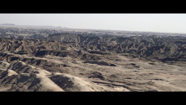 Video Reference: Badlands, Mountainous landforms, Sky, Aerial photography, Mountain, Mountain range, Geology, Canyon, Wadi, Formation, Outdoor, Photo, View, Flying, Air, Airplane, Large, Plane, Rocky, Covered, Water, Ocean, Man, White, Board, Skiing, Field, Standing, Group, Snow, Desert, Text, Nature
