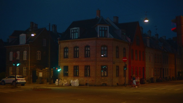 Video Reference: Night, Light, Sky, Lighting, Town, House, Building, Architecture, Home, Street light, Outdoor, Road, Street, Red, Car, Traffic, Intersection, Sitting, City, Side, Stop, Corner, Sign, View, Green, Yellow, Standing, Fire, Pole, Hydrant, Parked, Crowd