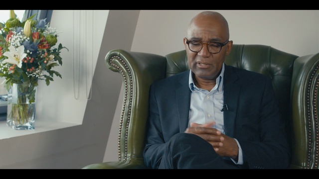 Video Reference: sitting, public speaking, gentleman, suit, official, speech, conversation, speaker, human behavior, communication, Person