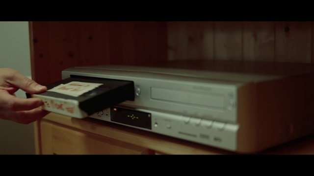 Video Reference: Electronics, Electronic device, Technology, Videocassette recorder, Dvd recorder, Indoor, Person, Cabinet, Kitchen, Food, Oven, Microwave, Front, Woman, Small, Sitting, Pizza, Holding, Stove, Man, Table, White, Standing, Wall, Text, Screenshot, Computer, Home appliance, Drawer