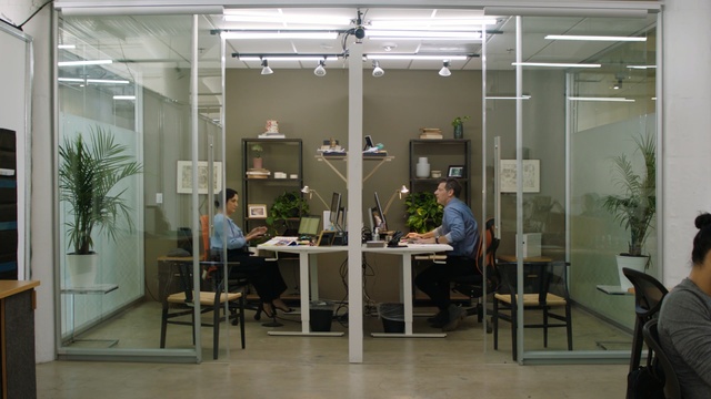 Video Reference: Building, Houseplant, Glass, Interior design, Office, Furniture, Indoor, Room, Table, Window, Chair, Living, Large, Filled, Area, Sitting, Computer, White, Dining, Black, Door, Man, Woman, Kitchen, Several, Group, Standing, Desk, People, Mirror, Holding, Floor, Clothing, Office building, Person, Shelf, Whiteboard