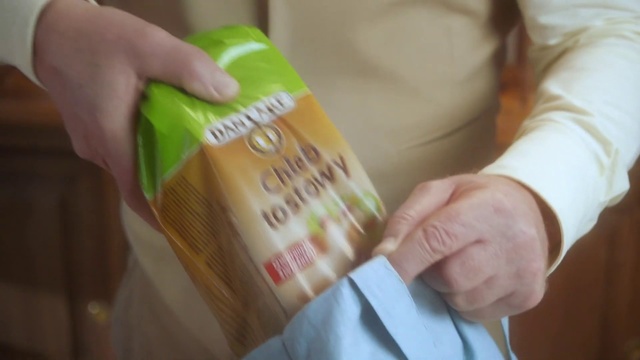 Video Reference: Hand, Person, Indoor, Holding, Small, Table, Sitting, Young, Little, Food, Boy, Man, Baby, Shirt, Bed, Woman, Standing, Remote, Refrigerator, Bottle, Soft drink, Text, Drink