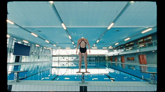 Video Reference: Swimming pool, Leisure centre, Leisure, Swimming, Swimmer, Recreation, Fun, Springboard, Diving, Building, Standing, Large, Front, Man, Court, Green, Water, Woman, Blue, City, Boat, Game, Holding, Playing, Bus, Room, Air, Riding, White, Airplane, Person, Clothing, Ceiling, Swimwear