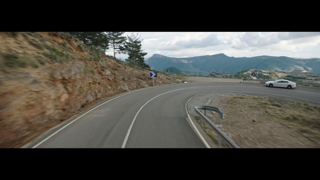 Video Reference: road, landscape, expressway, travel, highway, sky, asphalt, bend, journey, mountain, drive, clouds, trip, mountains, cloud, sand, transportation