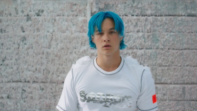 Video Reference: Hair, Blue, Turquoise, Cool, Chin, Forehead, T-shirt, Fashion, Neck, Electric blue, Person, Building, Outdoor, Clothing, Brick, Standing, Holding, Racket, Shirt, Young, Front, Stone, Man, Woman, Boy, Sweater, White, Black, Walking, Court, Playing, Phone, Ball, Board, Zoo, Human face, Sleeve