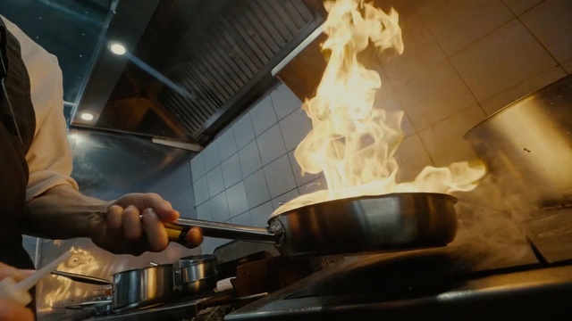 Video Reference: Cook, Cookware and bakeware, Food, Cooking, Wok, Cuisine, Dish, Chef, Teppanyaki, Indoor, Person, Kitchen, Man, Stove, Preparing, Pan, Making, Pulling, Hot, Large, Woman, Machine, Cooked, Stainless, Holding, Oven, Standing, Fire, Weapon, Flame, Meal