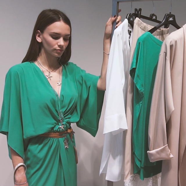 Video Reference: Clothing, Green, Turquoise, Dress, Robe, Fashion, Fashion design, Room, Outerwear, Boutique, Person, Indoor, Standing, Woman, Man, Wearing, Group, Photo, Posing, People, Holding, Clothes, Dressed, Hanging, White, Umbrella, Young, Large, Clothes hanger, Closet