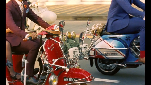 Video Reference: Motor vehicle, Vehicle, Scooter, Motorcycling, Motorcycle, Vespa, Mode of transport, Motorcycle accessories, Automotive design, Car, Person, Road, Outdoor, Riding, Man, Street, Red, Wearing, Woman, Suit, Sitting, Dressed, People, Officer, Standing, City, Land vehicle, Wheel, Tire, Bike, Motorbike, Auto part, Motor