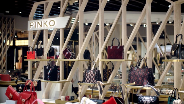 Video Reference: Building, Retail, Outlet store, Display window, Person, Table, Chair, Sitting, Computer, Front, Room, White, Large, Black, Laptop, Red, Desk, Wooden, Group, People, Umbrella, Bed, Man, Parked, Standing, Stuffed, Bear, Plate, Text