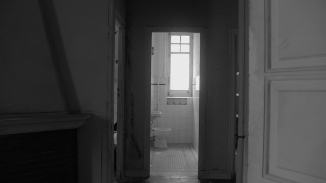 Video Reference: White, Black, Black-and-white, Light, Monochrome, House, Room, Door, Architecture, Darkness, Indoor, Window, Building, Floor, Photo, Small, Sitting, Doorway, Mirror, Sink, View, Open, Man, Table, Kitchen, Standing, Bathroom, Black and white, Plumbing fixture, Shower, Door handle, Tap