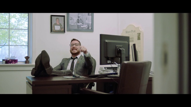 Video Reference: Room, Sitting, Furniture, Conversation, Photography, Desk, Interior design, White-collar worker, Screenshot, Indoor, Photo, Window, Living, Table, Man, Front, White, Cat, Computer, Wall, Office building, Television, Computer monitor, Person, Laptop, Human face