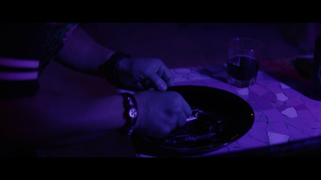 Video Reference: Purple, Violet, Black, Blue, Darkness, Light, Water, Photography, Fun, Space, Indoor, Table, Sitting, Glass, Wine, Dark, Lit, Man, Cake, Bowl, Holding, Large, Plate, Red, White, Pizza, Food, Standing, Room, Bottle