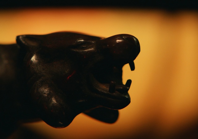 Video Reference: Snout, Sculpture, Sky, Art, Mouth, Big cats, Photography, Roar, Statue, Felidae, Black, Indoor, Sitting, Dark, Front, Looking, Background, Head, Table, Small, Yellow, Close, Face, Red, Eyes, Cat, Hat, Standing, Perched, Staring