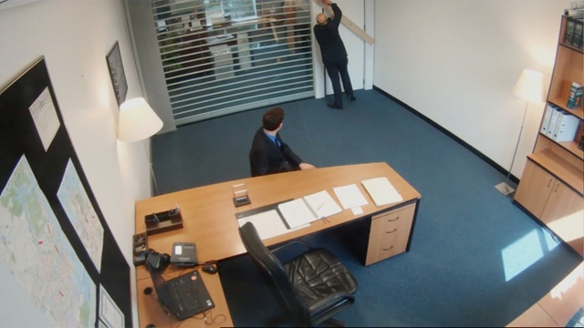 Video Reference: Floor, Room, Architecture, Office, Desk, Furniture, Flooring, Table, Interior design, Hardwood, Person