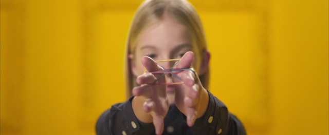 Video Reference: Face, Eyewear, Nose, Glasses, Vision care, Mouth, Finger, Gesture, Person, Indoor, Man, Young, Sitting, Holding, Table, Black, Looking, Front, Cake, Using, Eating, Drinking, Wearing, Food, Shirt, Yellow, Woman, Boy, Glass, Computer, Laptop, Room, Standing, Hat, Video, Remote, Game, Wall, Human face