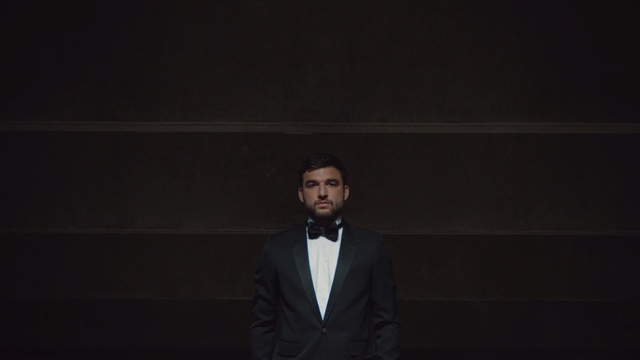 Video Reference: darkness, gentleman, facial hair, suit, night, performance, formal wear, public speaking, midnight, Person