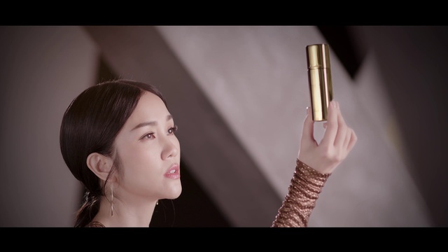 Video Reference: Hair, Face, Skin, Beauty, Nose, Eyebrow, Head, Lady, Hairstyle, Chin, Person, Indoor, Woman, Holding, Looking, Hand, Young, Girl, Wearing, Smiling, Standing, Shirt, Dark, White, Man, Pink, Room, Remote, Wall, Screenshot, Lipstick, Cosmetics, Human face, Fashion accessory