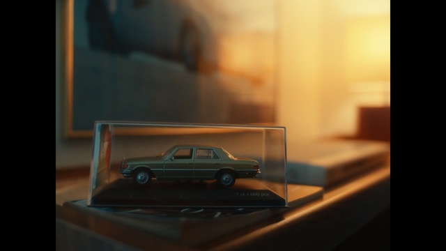 Video Reference: Toy vehicle, Car, Vehicle, Model car, Automotive design, Mode of transport, Automotive exterior, Scale model, Classic car, Sedan, Indoor, Sitting, Table, Front, Room, Computer, Mirror, View, Laptop, Light, Screen, Television, Black, Desk, Keyboard, Red, Living, Land vehicle, Wheel