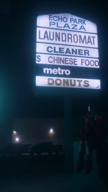 Video Reference: night, strip mall, sign, neon, laundromat, cleaner, chinese food, donuts, parking lot, urban, dark, foggy, commercial signage, person, street