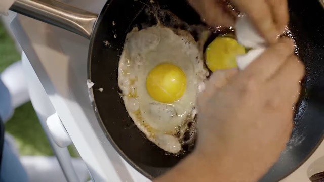 Video Reference: Dish, Food, Egg yolk, Pan frying, Egg, Ingredient, Fried egg, Cuisine, Frying, Breakfast, Person, Plate, Spoon, Table, Sitting, Black, Filled, Rice, Bowl, Holding, Pan, White, Man, Egg white, Boiled egg