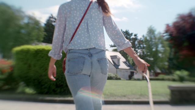 Video Reference: Clothing, Denim, Jeans, Street fashion, Fashion, Shirt, Outerwear, Waist, Trousers, Textile, Person, Outdoor, Road, Grass, Riding, Young, Girl, Woman, Wearing, Board, Game, Holding, Street, Standing, Man, Ball, Playing, White, Sky, Tree, Shorts, Skirt, Fashion accessory