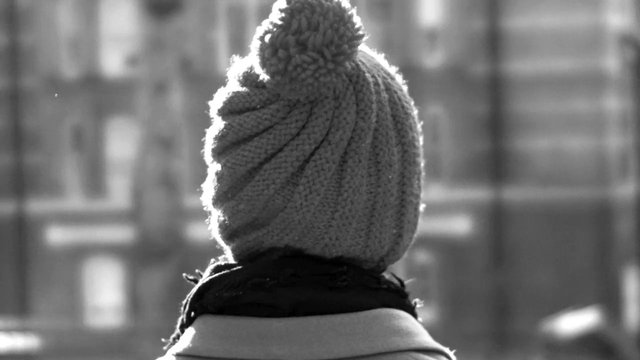 Video Reference: black and white, rear view, person, winter hat, knit cap, scarf, outdoor, blurred background, city, silhouette, cold weather, portrait