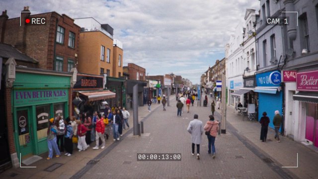 Video Reference: street, shopping district, pedestrians, storefronts, city, outdoor, crowd, commercial street, sidewalk, urban, daytime, cloudy sky, recording overlay, retail, walking, market street