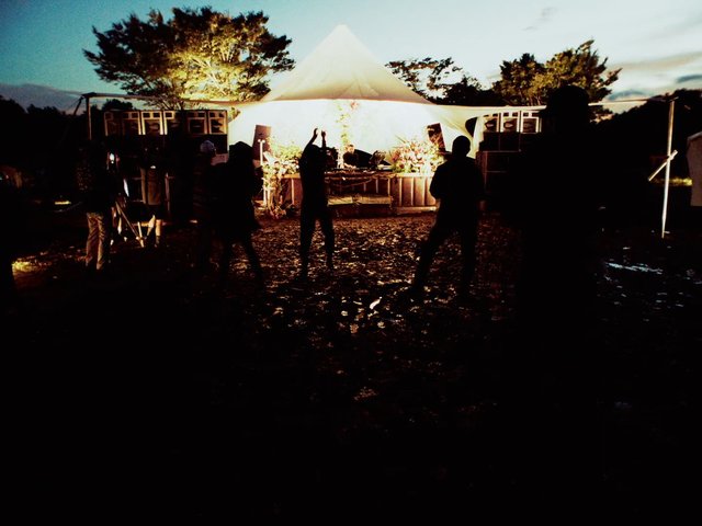 Video Reference: outdoor, night, tent, stage, silhouette, crowd, event, performance, lighting, speakers, dusk, festival, gathering, music, arena, backlit